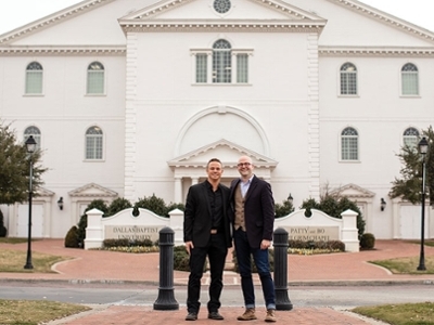 Two men are standing in front of the DBU Chapel.