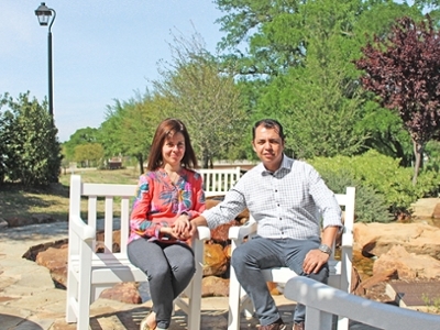 A man and his wife are sitting in chairs next to each other. They are holding hands and smiling. 