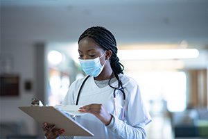 woman reading off a clip board in scrubs inside of a hospital